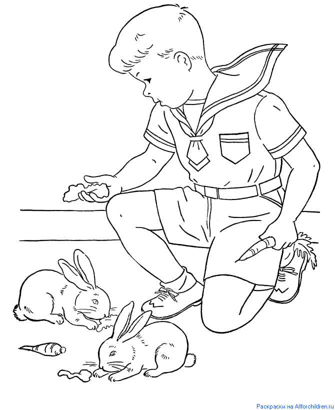 Мальчик кормит кроликов